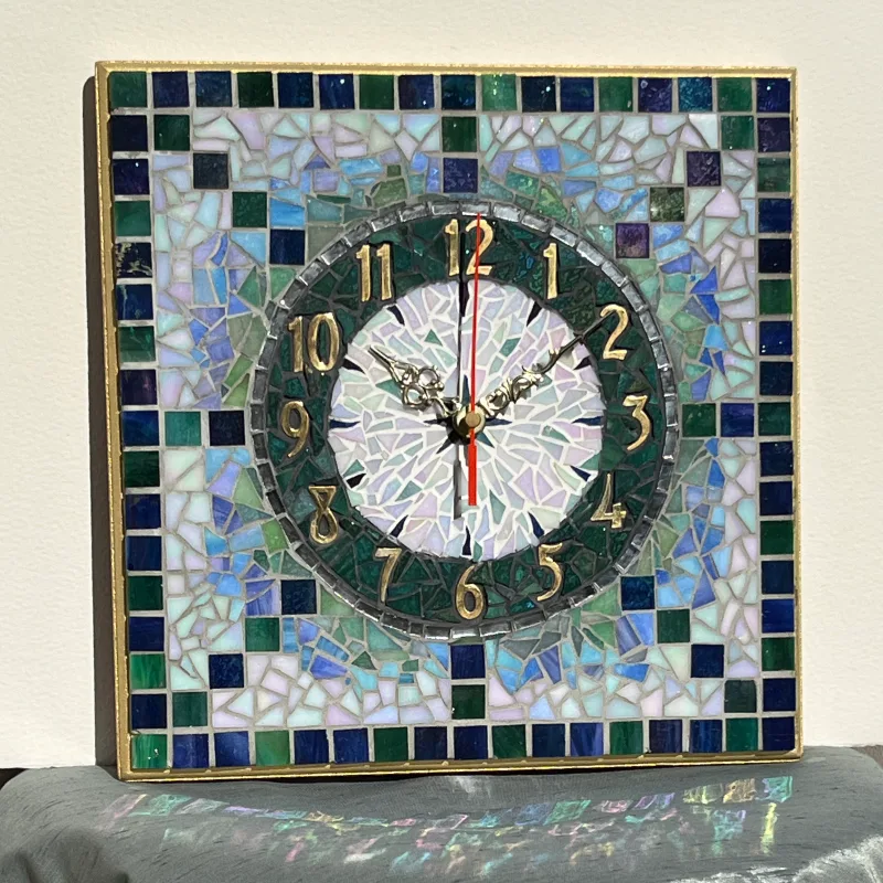 Handcrafted with iridescent green glass tiles, this wall clock catches and reflects light beautifully throughout the day.