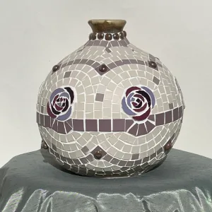 Crafted from an upcycled ceramic vase, its rounded body and slender neck are adorned with delicate lavender roses and imported tesserae in a classic Roman pattern.